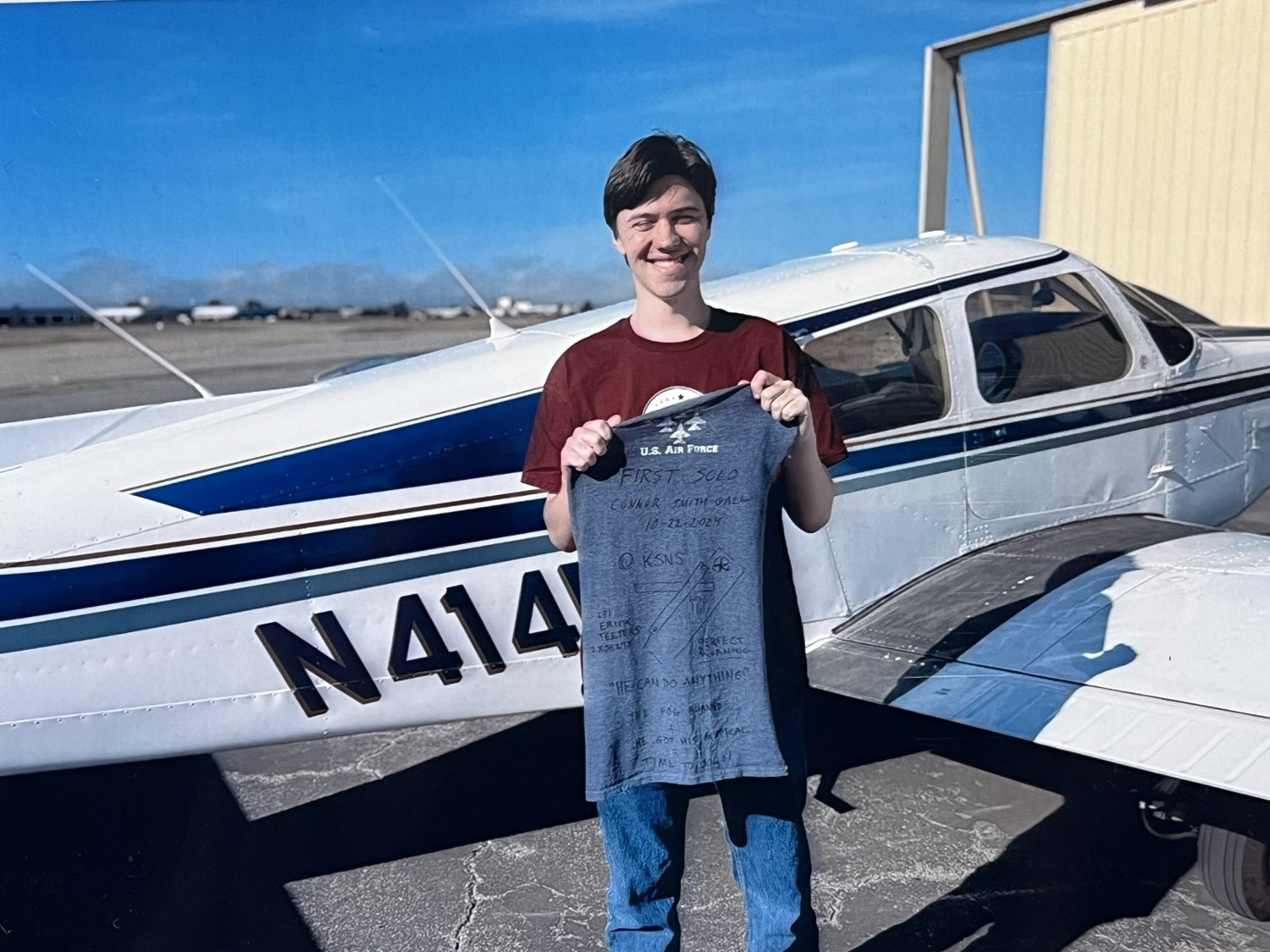 Connor smiling in front of the Warrior, holding up his signed solo shirt