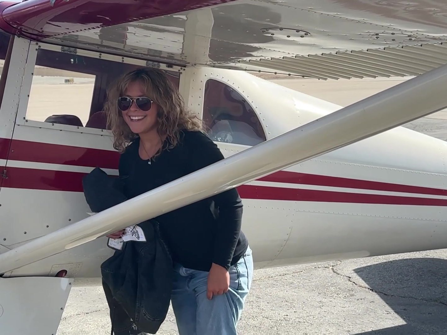 Hadley smiling beside the red-and-white Luscombe right after climbing out.